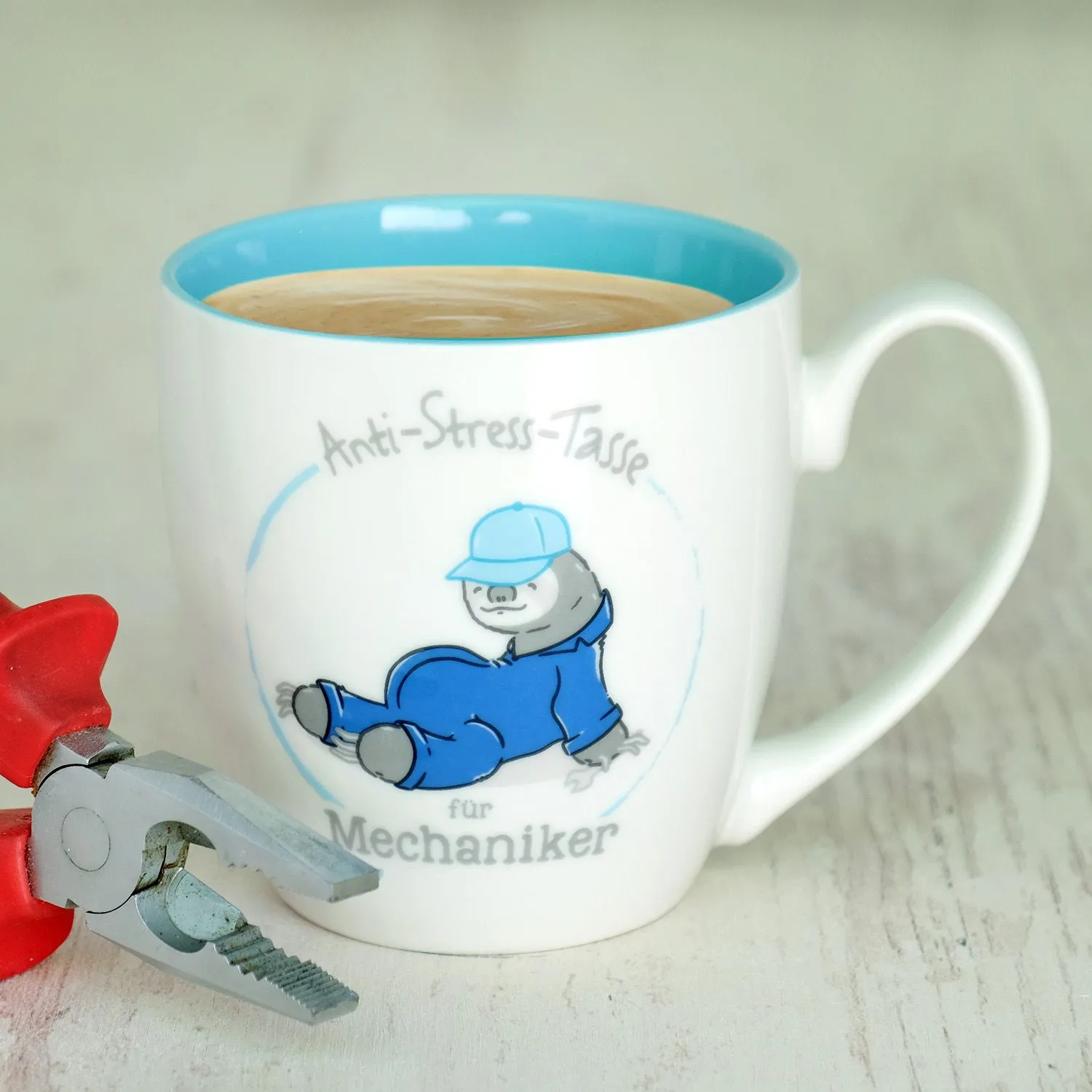 Weiße Keramik-Tasse mit blauem Innenraum und Mechaniker-Motiv